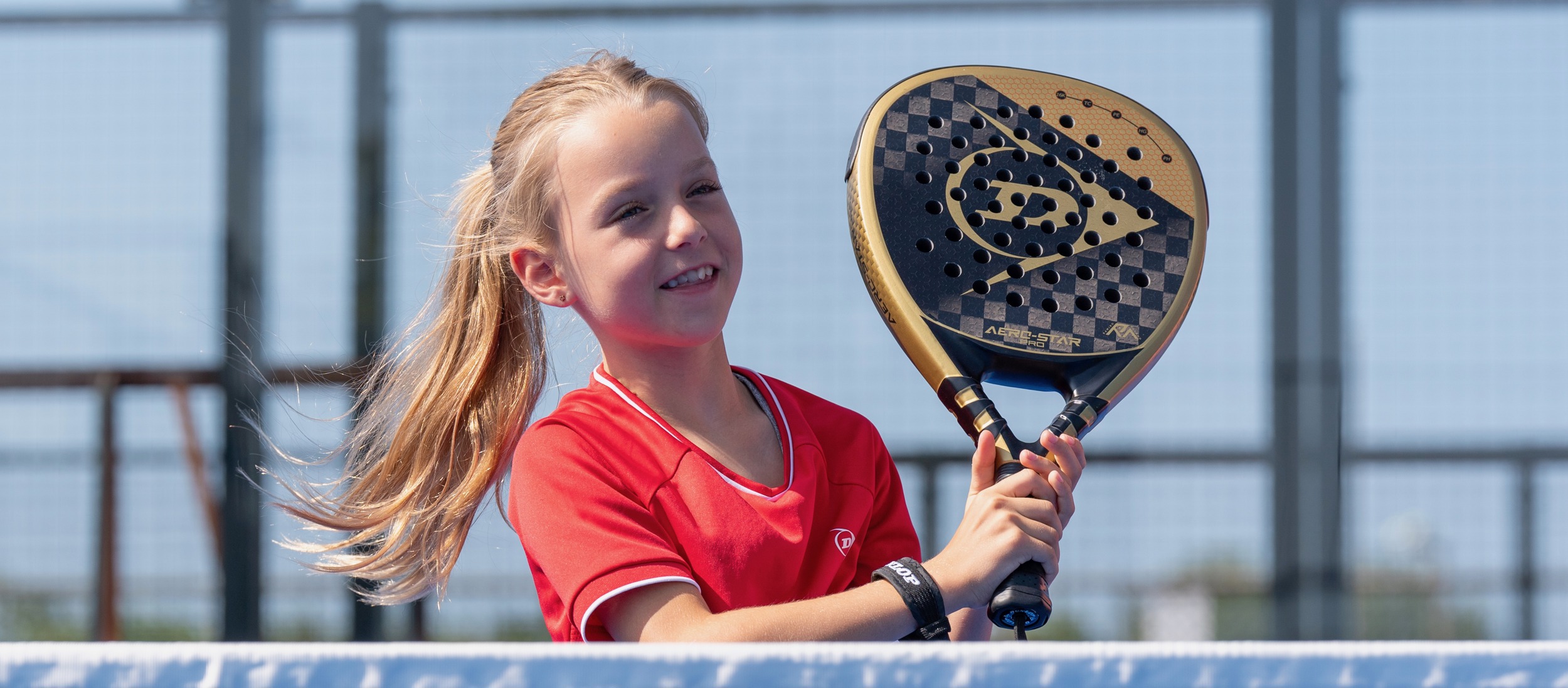 Meisje met padelracket aan het net